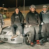 Vier junge Männer posieren im Schnee vor einem alten Honda