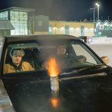 Zwei finnische Jugendliche in einem Auto mit einem Auspuff auf der Motorhaube, aus dem Flammen schlagen