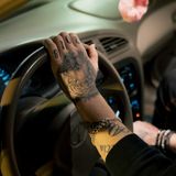 Detailaufnahme von dem Arm eines Autofahrers, der ein Löwen-Tatoo und die Zahl 2018 auf der Hand tättowiert hat.