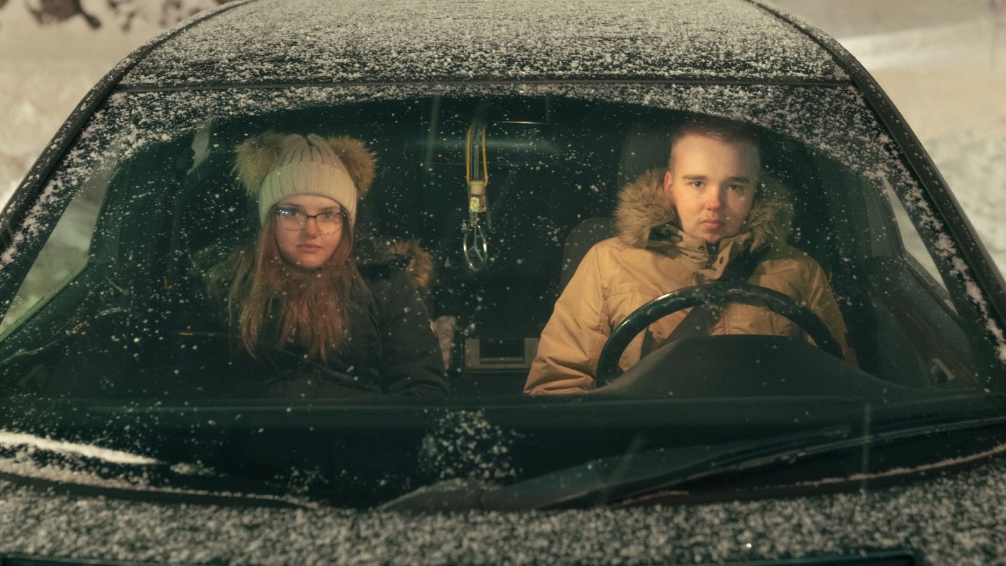 Ein Paar sitzt in einem halb zugeschneitem Auto