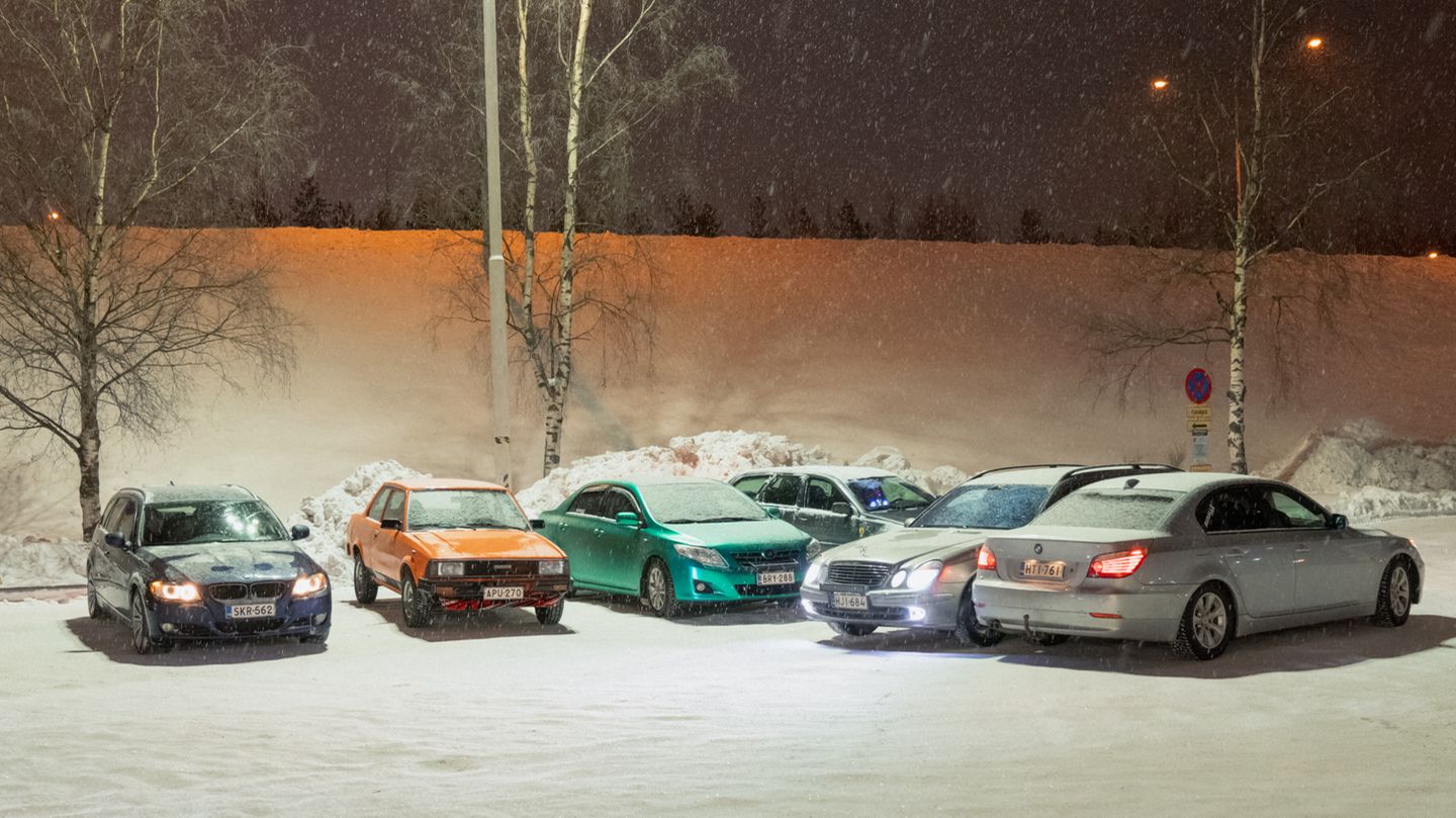 sechs halb zugeschneite Autos auf einem Parkplatz im Finnischen Umland
