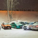 sechs halb zugeschneite Autos auf einem Parkplatz im Finnischen Umland