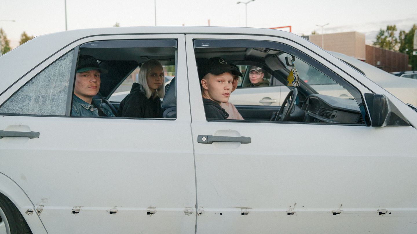 4 Jugentliche sitzen in einem alten Auto und schauen in die Kamera