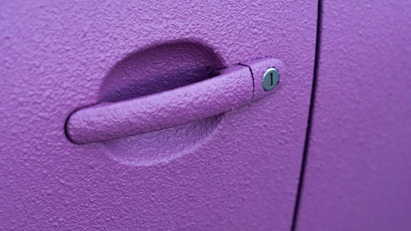 eine Nahaufnahme von einem lila Auto-Türgriff