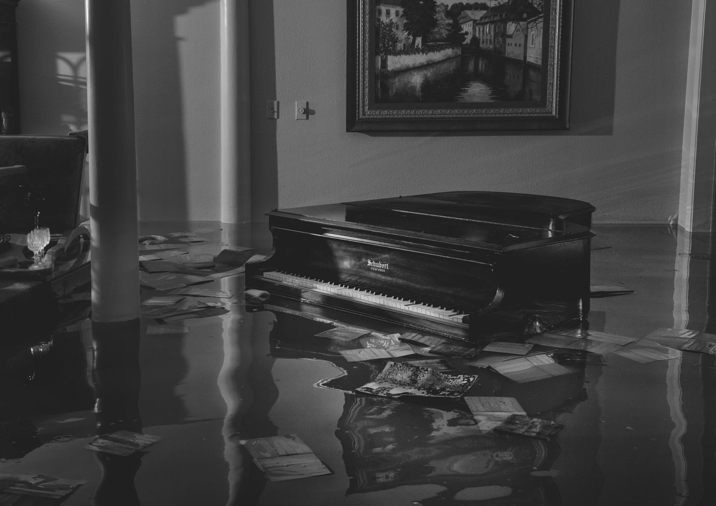 Ein Flügel steht in einem überfluteten Wohnzimmer, drum herum schwimmen Papiere und Hefte