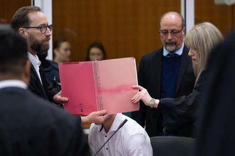 Anwälte von einem der acht Angeklagten halten ihrem Mandanten eine Akte vors Gesicht, um ihn von den Kameras abzuschirmen