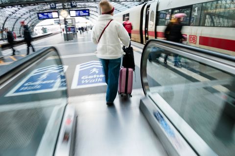Eine Reisende fährt am Berliner Hauptbahnhof mit ihrem Koffer eine Rolltreppe zum Bahnsteig hinauf. Foto: Carsten Koall/dpa