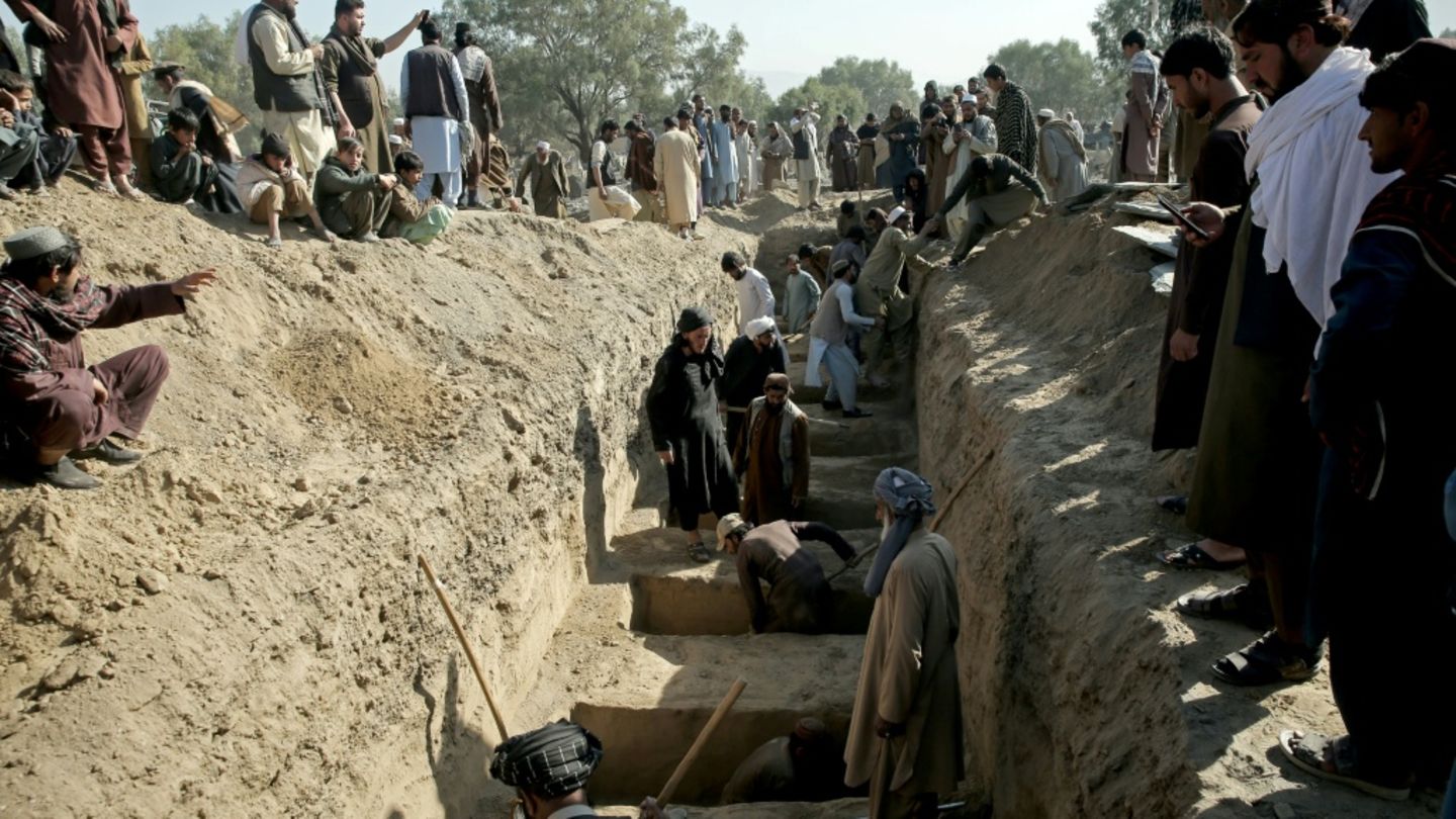 Bewohner von Bishud an einem Sammelgrab für die Getöteten