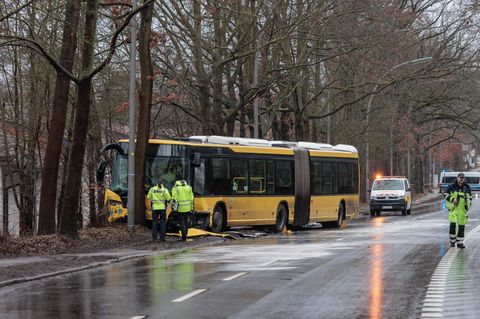 Polizisten stehen an der Unfallstelle vor dem beschädigten Bus. Foto: Carsten Koall/dpa