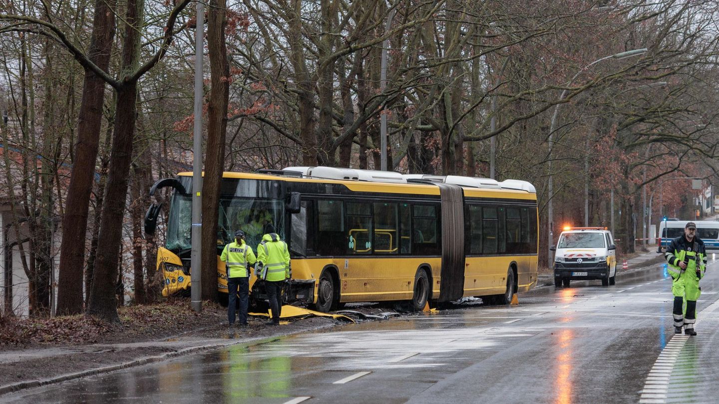 Polizisten stehen an der Unfallstelle vor dem beschädigten Bus. Foto: Carsten Koall/dpa