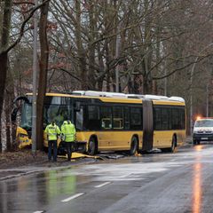 Polizisten stehen an der Unfallstelle vor dem beschädigten Bus. Foto: Carsten Koall/dpa