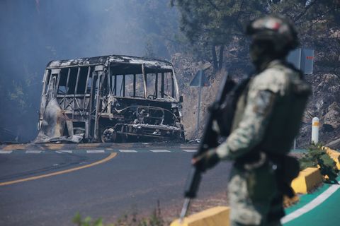 Ein Soldat steht in Mexiko - einem der drei Ausrichterländer der Fußball-WM im Sommer - neben einem ausgebrannten Bus. Foto: Arm
