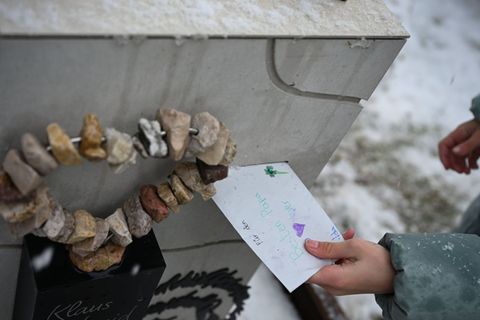 Die zehnjährige Ida wirft einen Brief an ihren Vater in den Briefschlitz am Grabstein. Foto: Katharina Kausche/dpa