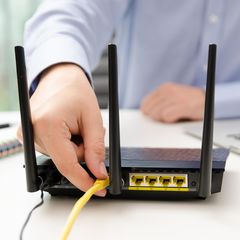 Der Mann steckt ein Ethernet-Kabel in den Router.