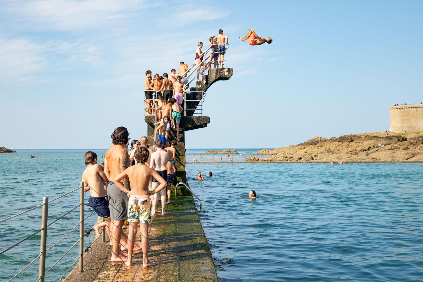 Menschen stehen Schlange an einem Sprungbrett am Meer
