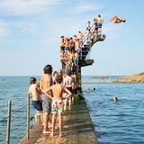Menschen stehen Schlange an einem Sprungbrett am Meer