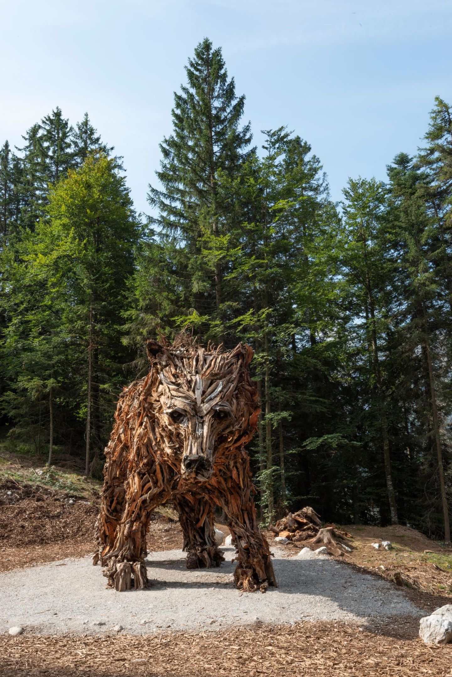 Eine Bärenfigur aus Holz steht im Wald