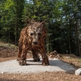 Eine Bärenfigur aus Holz steht im Wald