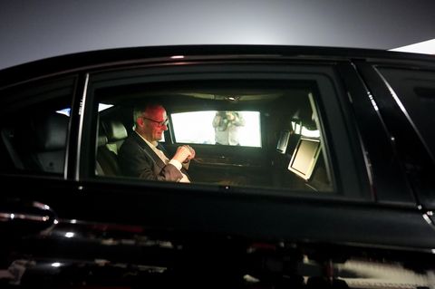 China: Merz sitzt in einem schwarzen Auto. Sein Gesicht wird von einem roten Licht erhellt.