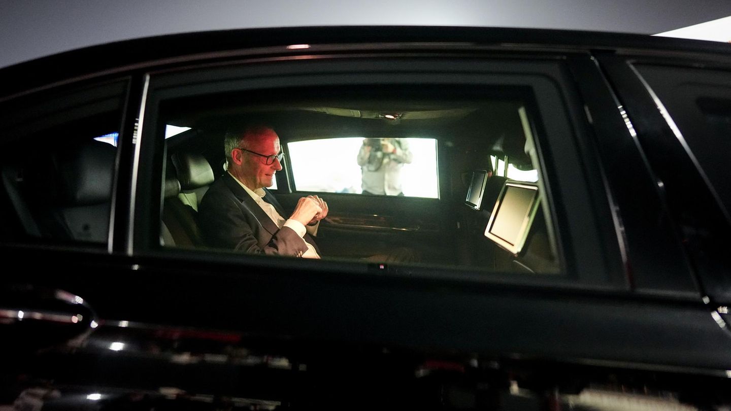 China: Merz sitzt in einem schwarzen Auto. Sein Gesicht wird von einem roten Licht erhellt.