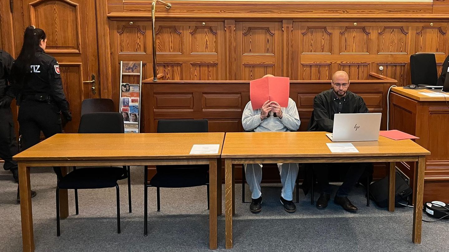 Ein Mann hält sich einen Aktenordner vors Gesicht / Prozessauftakt Ehrenmord