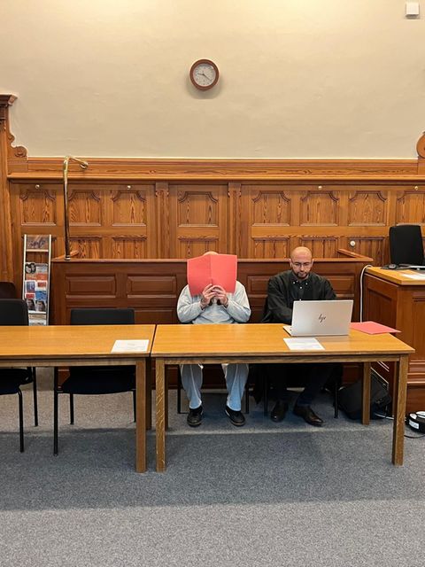 Ein Mann hält sich einen Aktenordner vors Gesicht / Prozessauftakt Ehrenmord