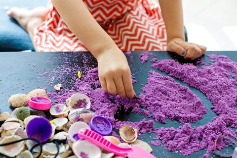 Spielzeug: Ein Kind spielt mit farbigem Sand