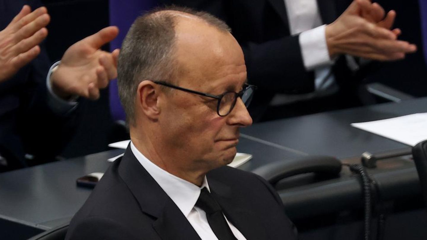 Friedrich Merz sitzt im Plenarsaal des Deutschen Bundestages, während die Abgeordneten um ihn herum applaudieren