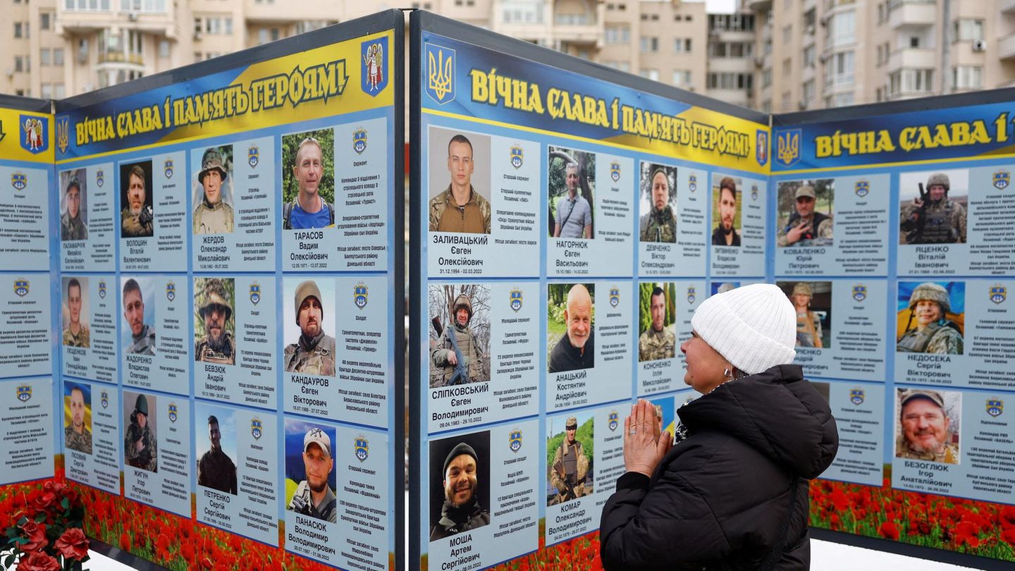 Kiew, Ukraine. Am vierten Jahrestag der russischen Invasion betet und trauert eine Frau vor dem Foto eines Angehörigen am Denkmal für gefallene ukrainische Soldaten in der Hauptstadt. Die Porträts der Verteidiger erzählen von ihrem Opfer und der ungebrochenen Trauer.