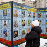 Kiew, Ukraine. Am vierten Jahrestag der russischen Invasion betet und trauert eine Frau vor dem Foto eines Angehörigen am Denkmal für gefallene ukrainische Soldaten in der Hauptstadt. Die Porträts der Verteidiger erzählen von ihrem Opfer und der ungebrochenen Trauer.