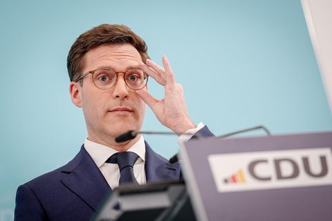 Manuel Hagel rückt sich hinter einem Rednerpult mit CDU-Logo mit links die Brille zurecht