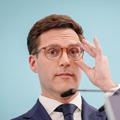 Manuel Hagel rückt sich hinter einem Rednerpult mit CDU-Logo mit links die Brille zurecht