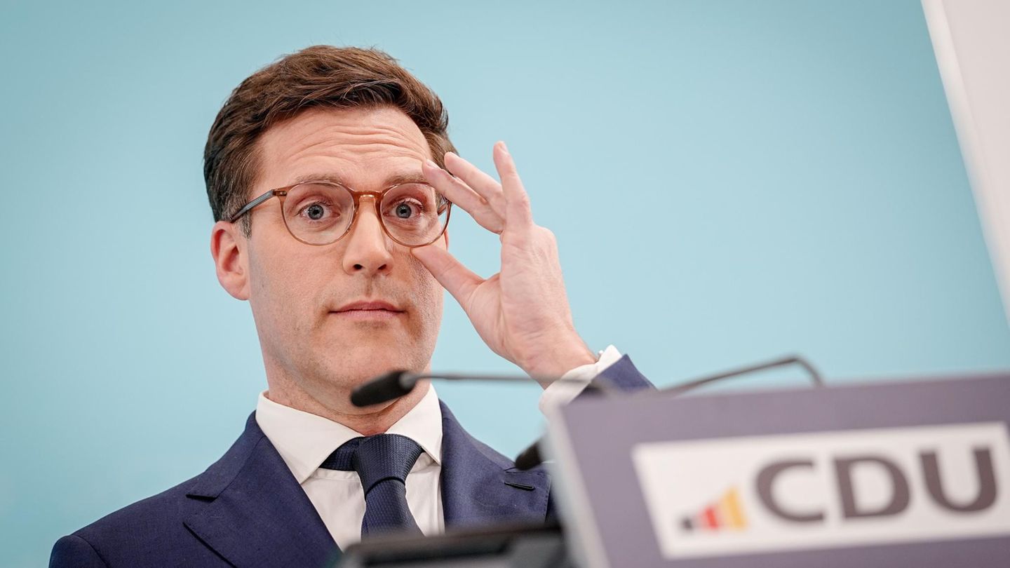 Manuel Hagel rückt sich hinter einem Rednerpult mit CDU-Logo mit links die Brille zurecht