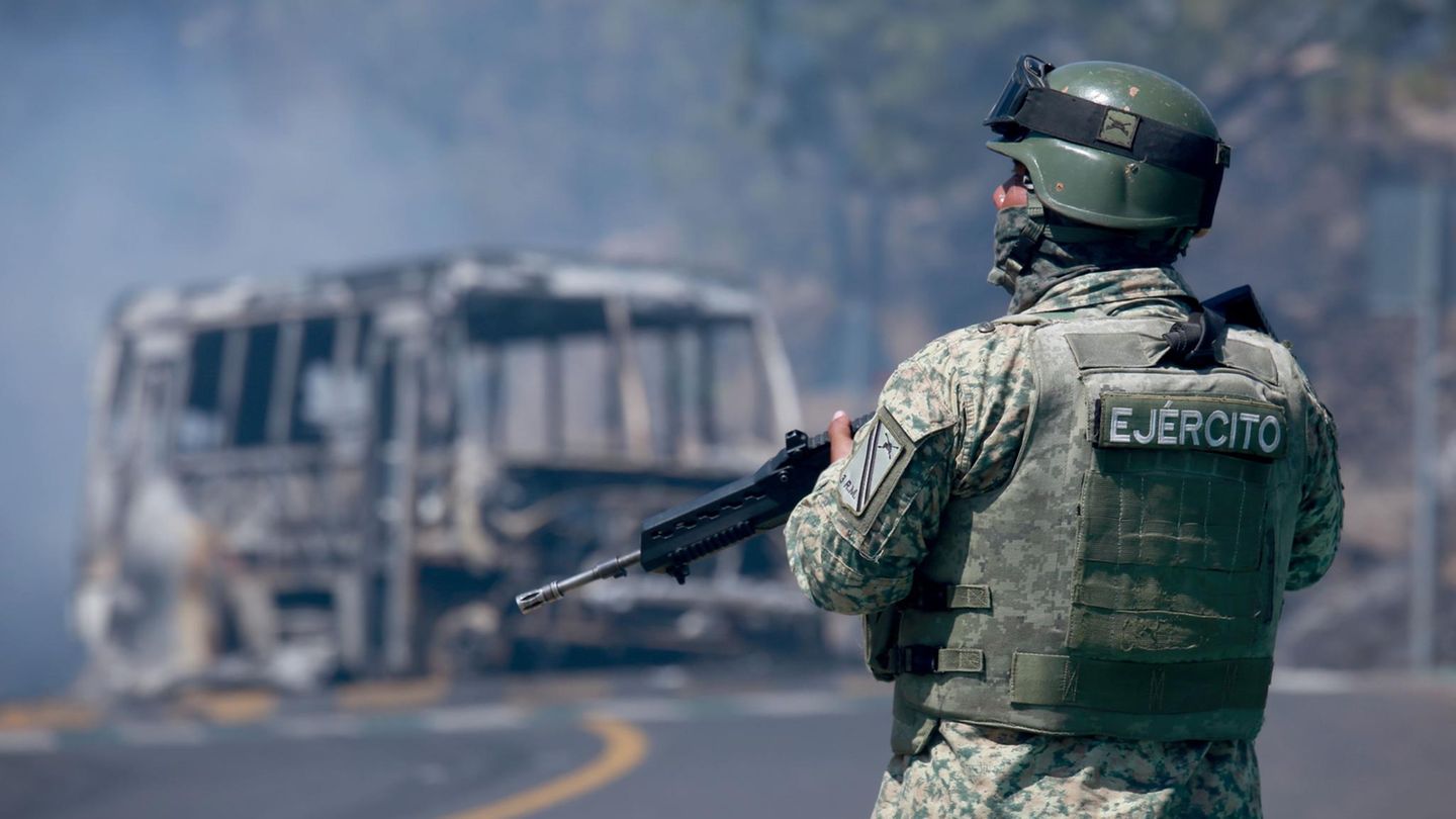 Ein Soldat steht neben einem ausgebrannten Bus in Cointzio im mexikanischen Bundesstaat Michoacán