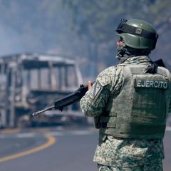 Ein Soldat steht neben einem ausgebrannten Bus in Cointzio im mexikanischen Bundesstaat Michoacán