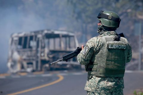 Ein Soldat steht neben einem ausgebrannten Bus in Cointzio im mexikanischen Bundesstaat Michoacán