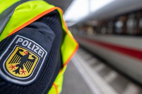 Ein Polizist steht an einem Bahnhof neben einem Zug