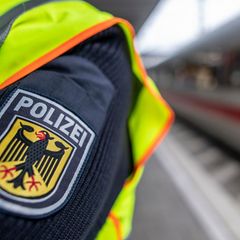 Ein Polizist steht an einem Bahnhof neben einem Zug