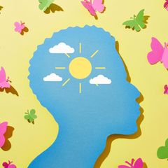 Glück: Illustration eines Kopfes umgeben von Sonnenschein und Schmetterlingen