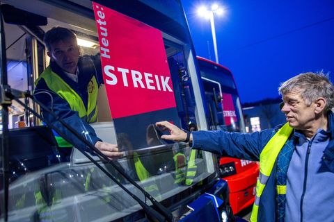 Mitarbeiter befestigen auf dem Betriebshof in Schwerin ein Streik-Plakat an der Frontscheibe einer Straßenbahn. Foto: Jens Büttn