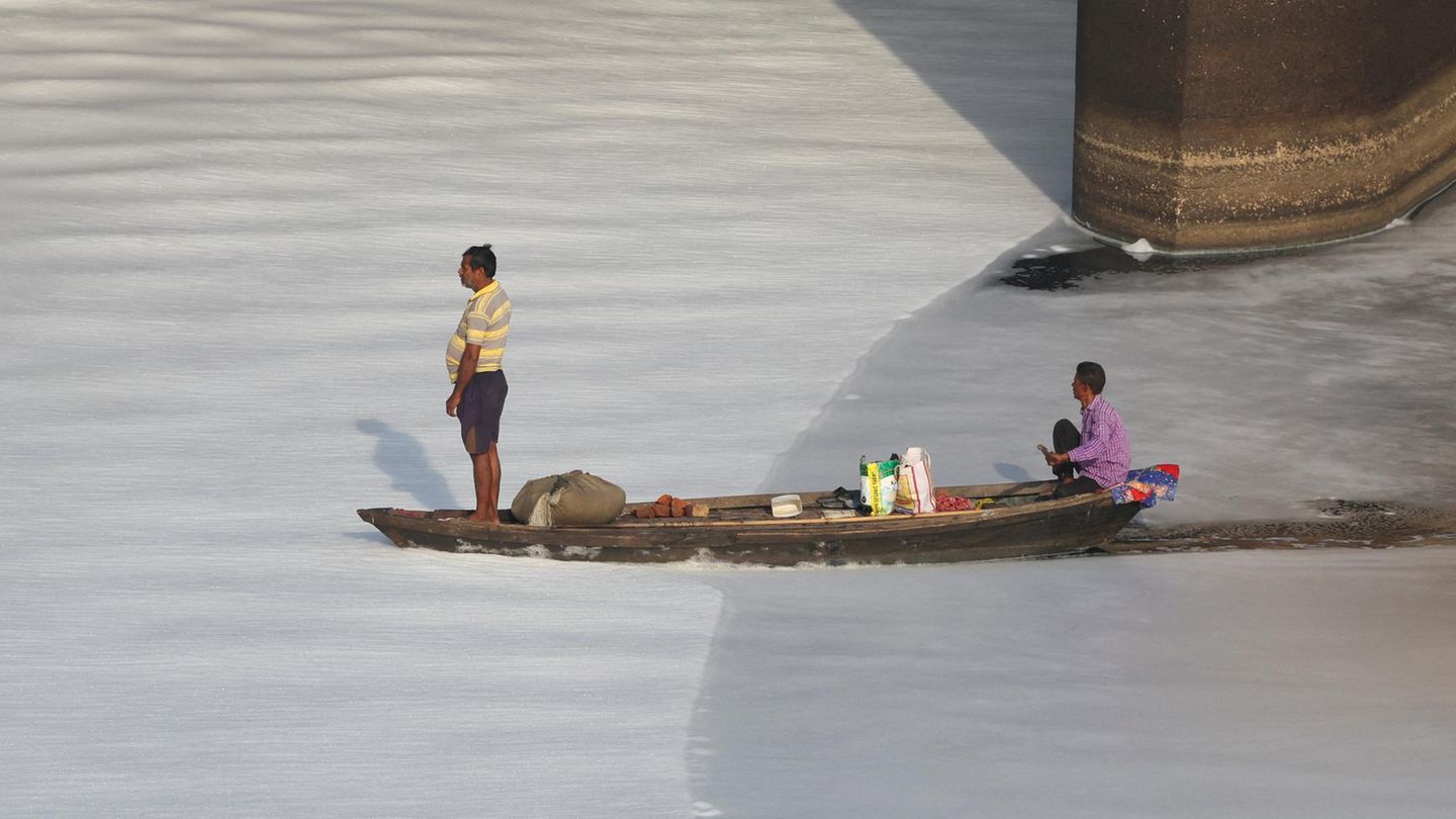 Neu-Delhi, Indien. Schaum so weit das Auge reicht: Zwei Fischer fahren mit einem Boot durch den verschmutzten Yamuna-Fluss in der Hauptstadt. Er ist der wichtigste Nebenfluss des Ganges und gilt als einer der giftigsten Flüsse weltweit.