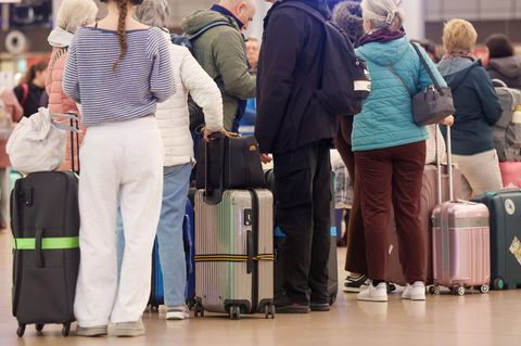 Reisende stehen an einem Flughafen in einer Schlange