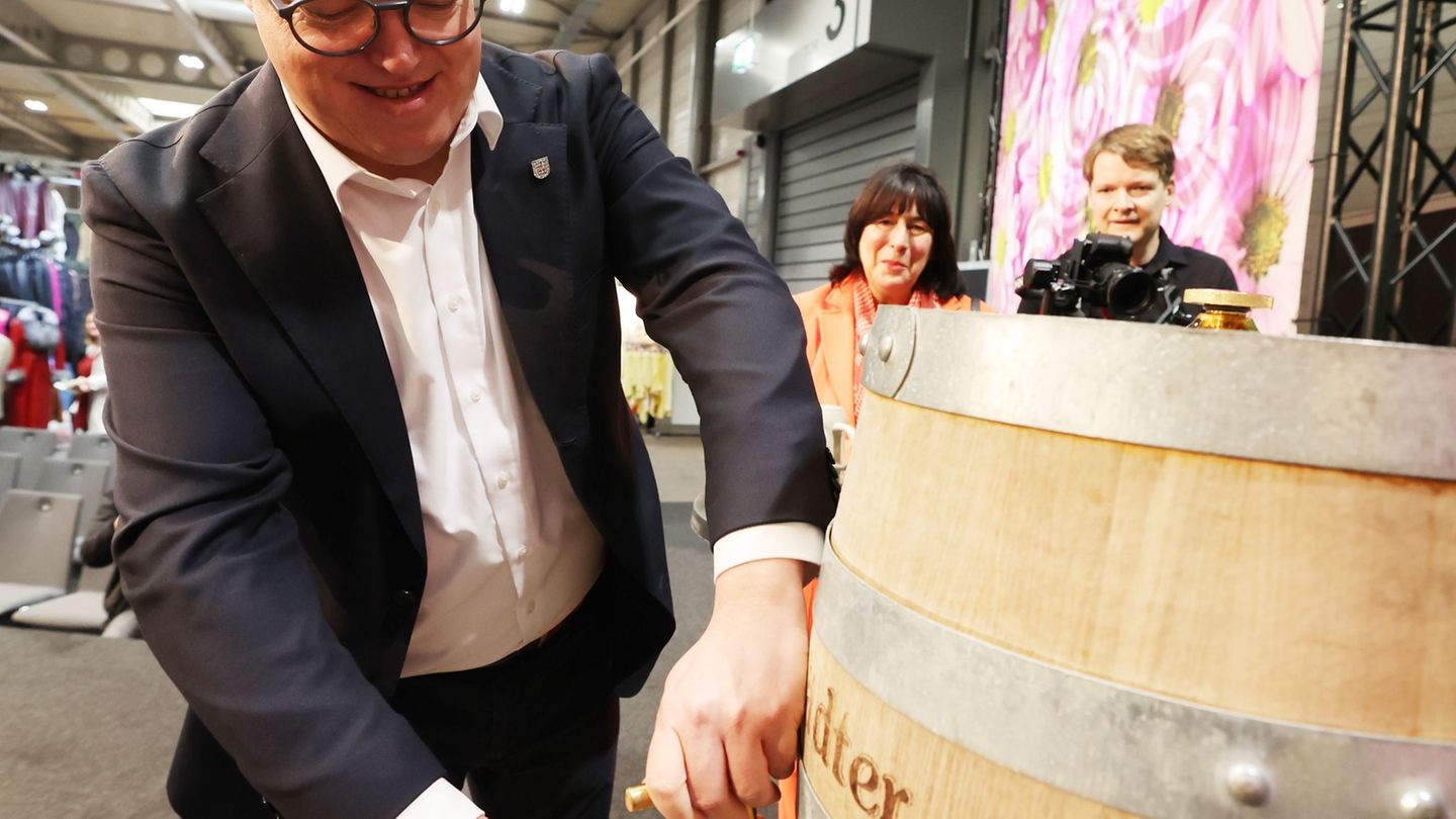 Thüringens Ministerpräsident Mario Voigt schlug bei der "Thüringen-Ausstellung" ein Bierfass an. Foto: Bodo Schackow/dpa