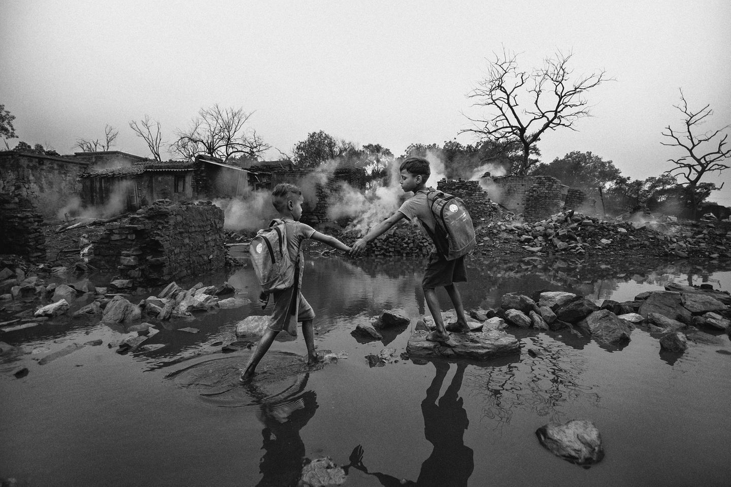 Wir erfahren nicht, was in diesem indischen Dorf geschehen ist. Aber Fotograf Sourav Das zeigt uns die Zerstörung: Eingestürzte Mauern, abgestorbene Bäume, wabernde Rauchschwaden. Durch diese postapokalyptische Welt kämpfen sich zwei Jungen, Hand in Hand, als sei die Hölle nur ein Abschnitt auf ihrem Schulweg. „Die Welt um sie herum mag zerstört sein, aber ihr Instinkt, füreinander zu sorgen, bleibt ungebrochen", schreibt die Jury. „Dieser Moment erinnert uns daran, dass Güte nicht nur eine Geste ist, sondern eine Form des Überlebens." Sie heilt Wunden und gibt uns die Kraft, aus Ruinen eine neue, bessere Welt zu erschaffen.
