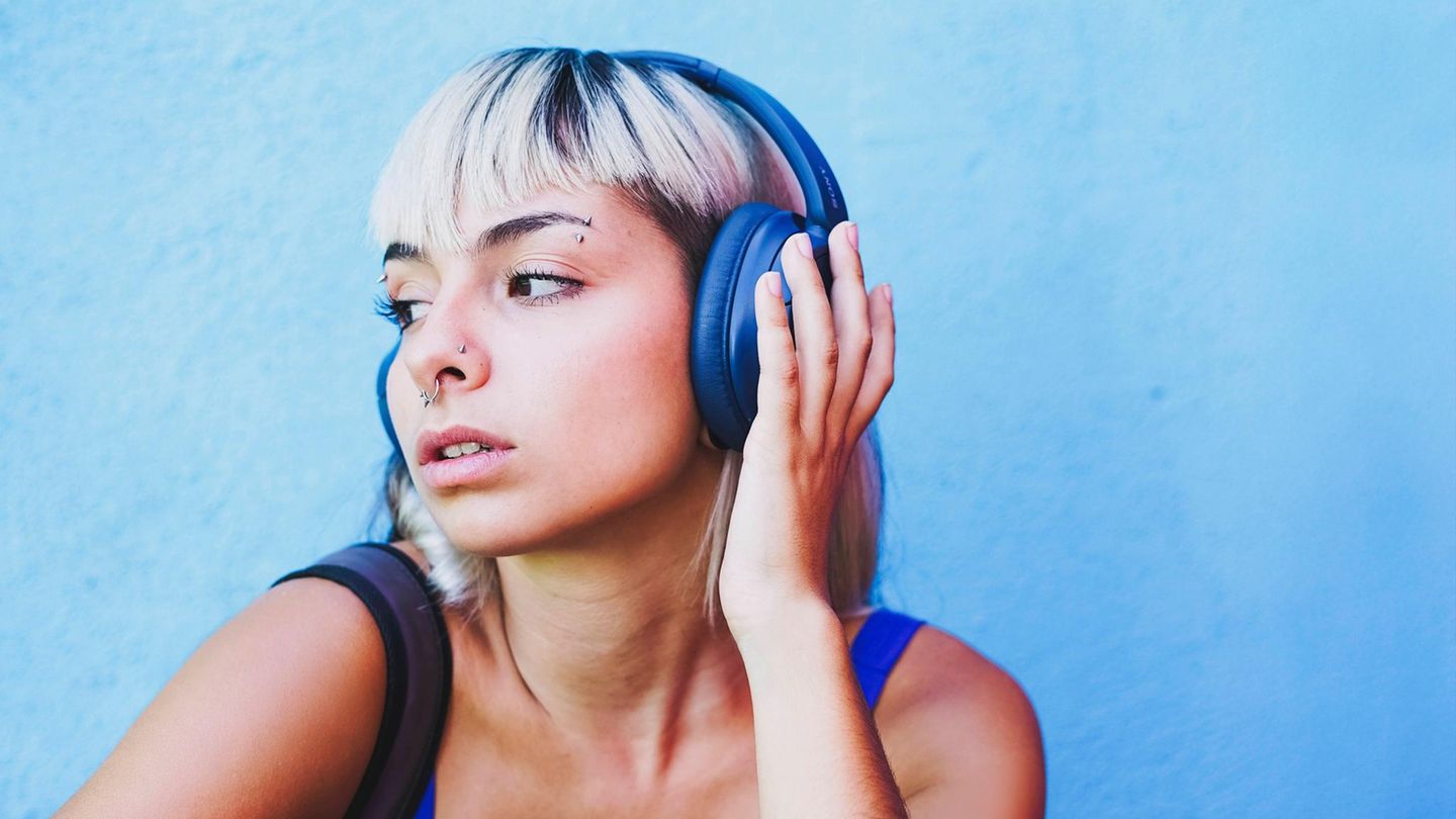 Eine Frau hat blaue Kopfhörer auf und hört Musik