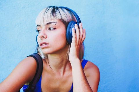 Eine Frau hat blaue Kopfhörer auf und hört Musik