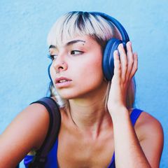Eine Frau hat blaue Kopfhörer auf und hört Musik