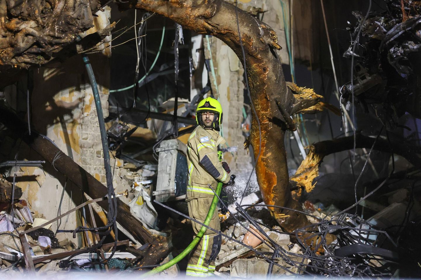 Der Iran antwortet mit Raketenangriffen auf Israel und seine Nachbarländer. Hier löscht ein Feuerwehrmann einen Brand nach einem Einschlag in Gush Dan, einem Viertel von Tel Aviv.