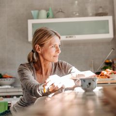 Ehe: Eine Frau sitzt an einem Tisch in einer Küche