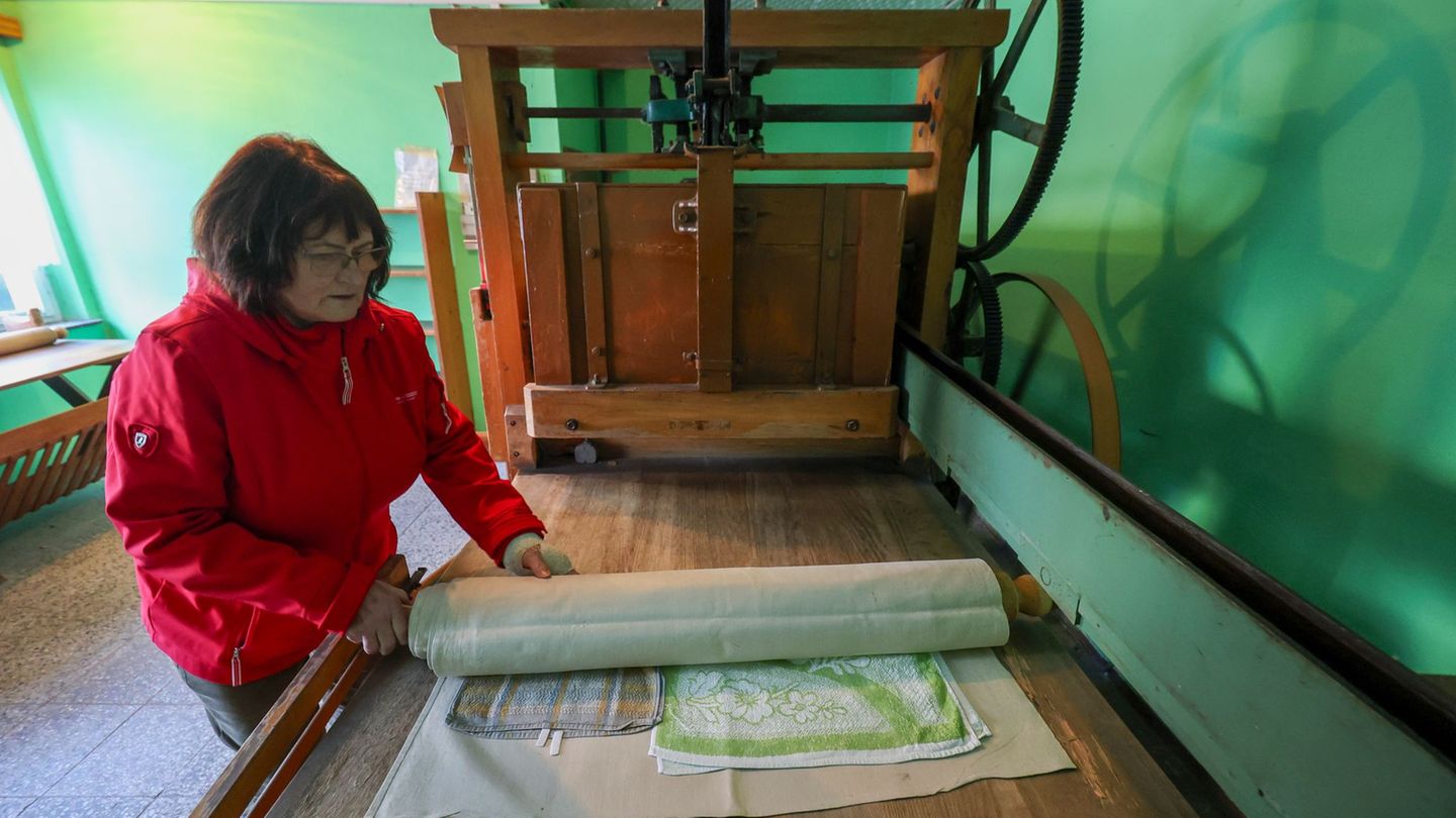 Annerose Illing mangelt die Wäsche ihrer betagten Mutter mit einer historischen Kaltmangel. Foto: Jan Woitas/dpa